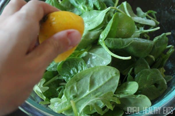 Simple Spinach & Arugula Salad 把柠檬挤在菠菜和芝麻菜上的图片