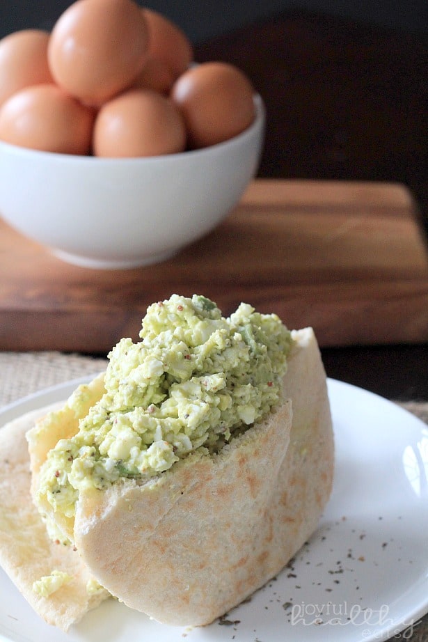 Avocado Egg Salad 在一块板材的鸡蛋沙拉三明治旁边一碗鸡蛋