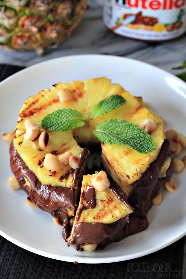 Grilled Pineapple with Nutella & Macadamia Nuts #dessert #healthy #grilled #pineapple #nutella 顶部视图烤菠萝与Nutella和澳洲坚果在盘子上与楔形切割