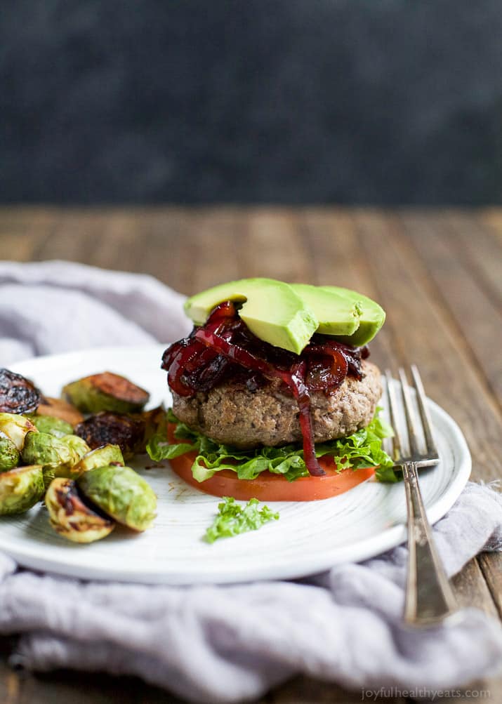 Paleo Burgers with Caramelized Balsamic Onions 一个带有叉子的盘子上的古汉堡的图像
