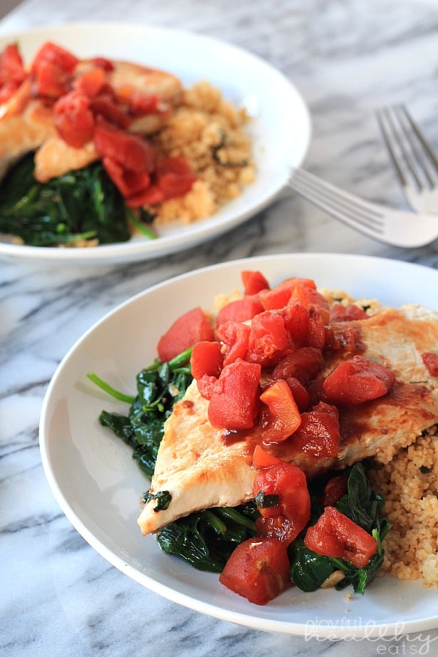Balsamic Chicken with Baby Spinach and diced tomatoes on a plate with couscous