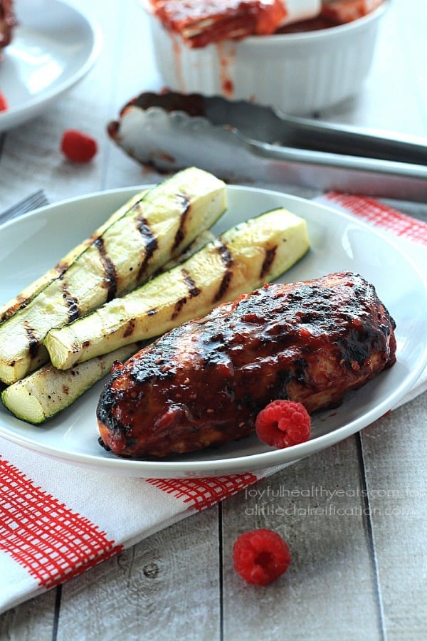 Grilled Chicken Breasts with Raspberry Chipotle BBQ Sauce 一盘烤墨西哥烤鸡旁边有四条烤西葫芦条