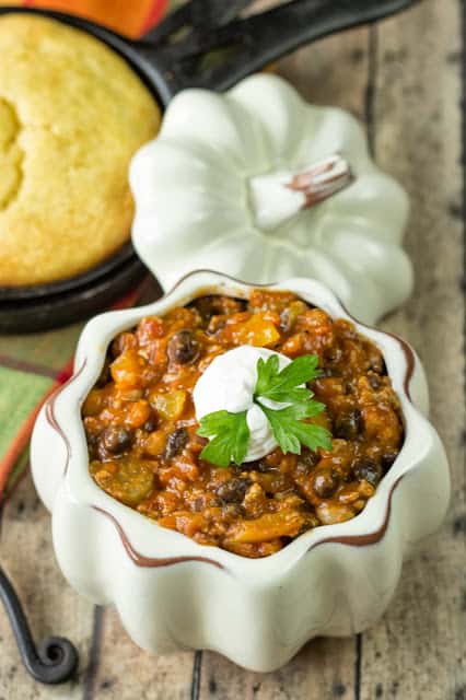 30 of The Best Pumpkin Recipes for Fall 南瓜火鸡辣椒在白色南瓜形状的碗里,上面有酸奶油