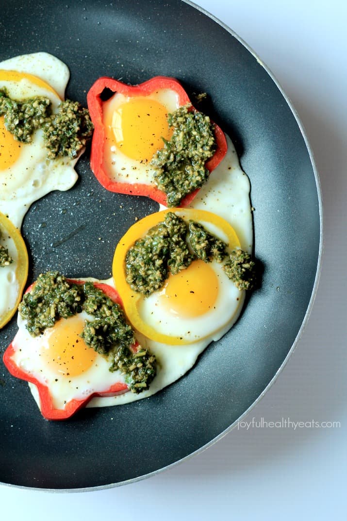 Egg in a Hole with Basil Pesto, seriously one of my healthy breakfast recipes | m.albarakaa.com 顶部视图蛋在一个洞与罗勒香蒜酱和柿子椒环在煎锅