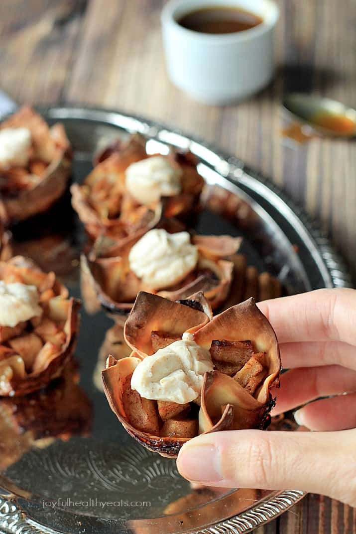 Try to stop at just one of these Caramel Apple Pie Wonton Cups with a Honey Cinnamon Mascarpone, good luck! | m.albarakaa.com 一只手拿着焦糖苹果派云吞杯,上面有蜂蜜肉桂马斯卡彭干酪