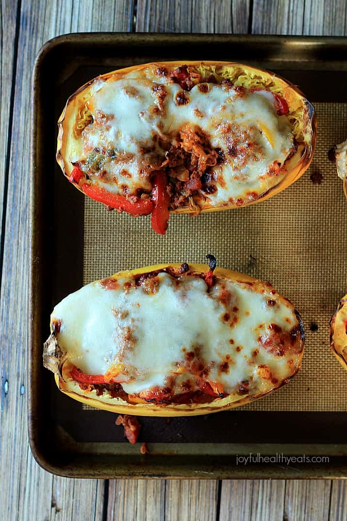 An easy healthy spanish inspired weeknight dinner, Chorizo Kale & Pepper Stuffed Spaghetti Squash Boats! | m.albarakaa.com 在烤盘上的西班牙辣香肠甘蓝和胡椒填充意大利面南瓜船的俯视图