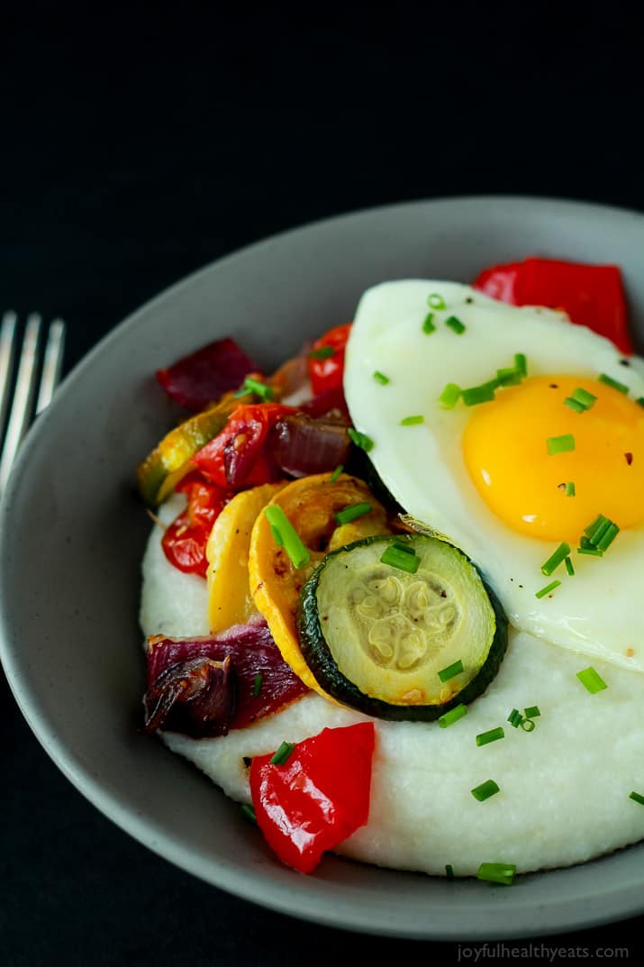 Creamy Goat Cheese Grits and Eggs with Roasted Vegetables 黑色背景下的一碗山羊奶酪粉和鸡蛋
