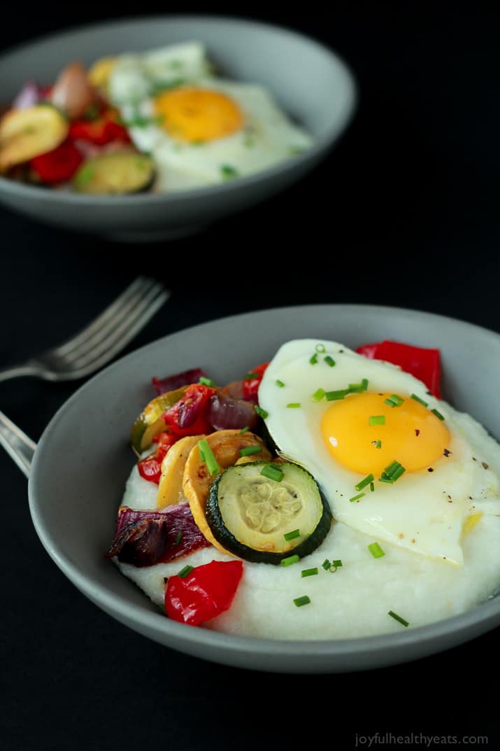 Creamy Goat Cheese Grits and Eggs with Roasted Vegetables 两碗鸡蛋蔬菜磨粉在两把叉子旁边