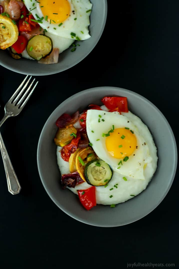 Creamy Goat Cheese Grits and Eggs with Roasted Vegetables 两碗灰色的面粉,鸡蛋和蔬菜和银器