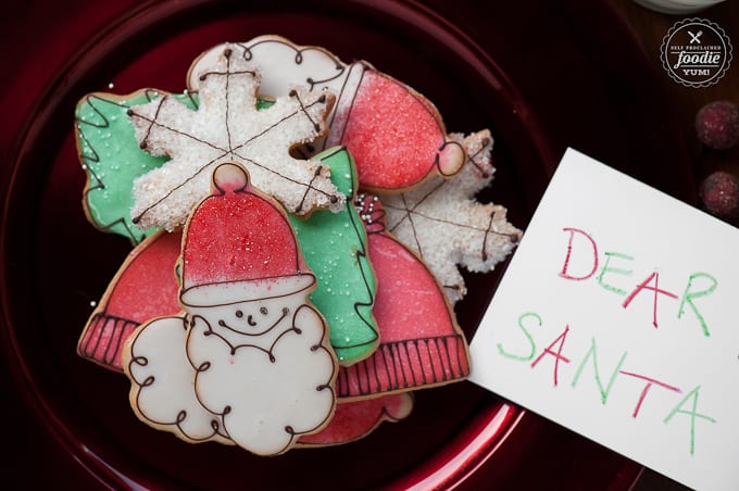 35 Must Have Christmas Cookie Recipes 圣诞老人标牌旁边的一盘节日糖饼干