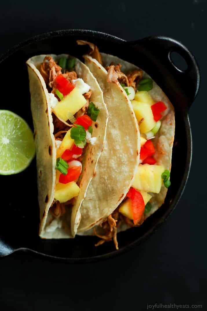 An easy Crock Pot Recipe your family will love! Hawaiian Pork Tacos filled with sweet pulled pork, fresh pineapple, red peppers, and goat cheese for a fun twist!! |joyfulhealthyeats.com #recipes Top view of two Hawaiian Pork Tacos filled with sweet pulled pork, fresh pineapple, red peppers, and goat cheese