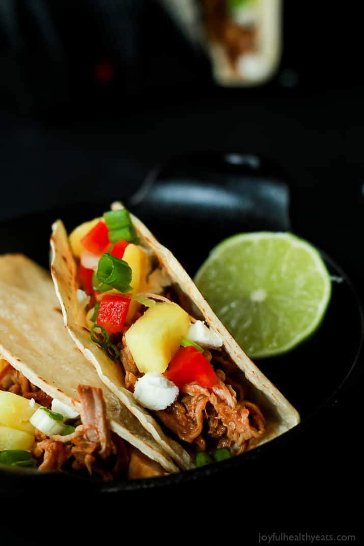 An easy Crock Pot Recipe your family will love! Hawaiian Pork Tacos filled with sweet pulled pork, fresh pineapple, red peppers, and goat cheese for a fun twist!! |joyfulhealthyeats.com #recipes Two Hawaiian Pork Tacos filled with sweet pulled pork, fresh pineapple, red peppers, and goat cheese