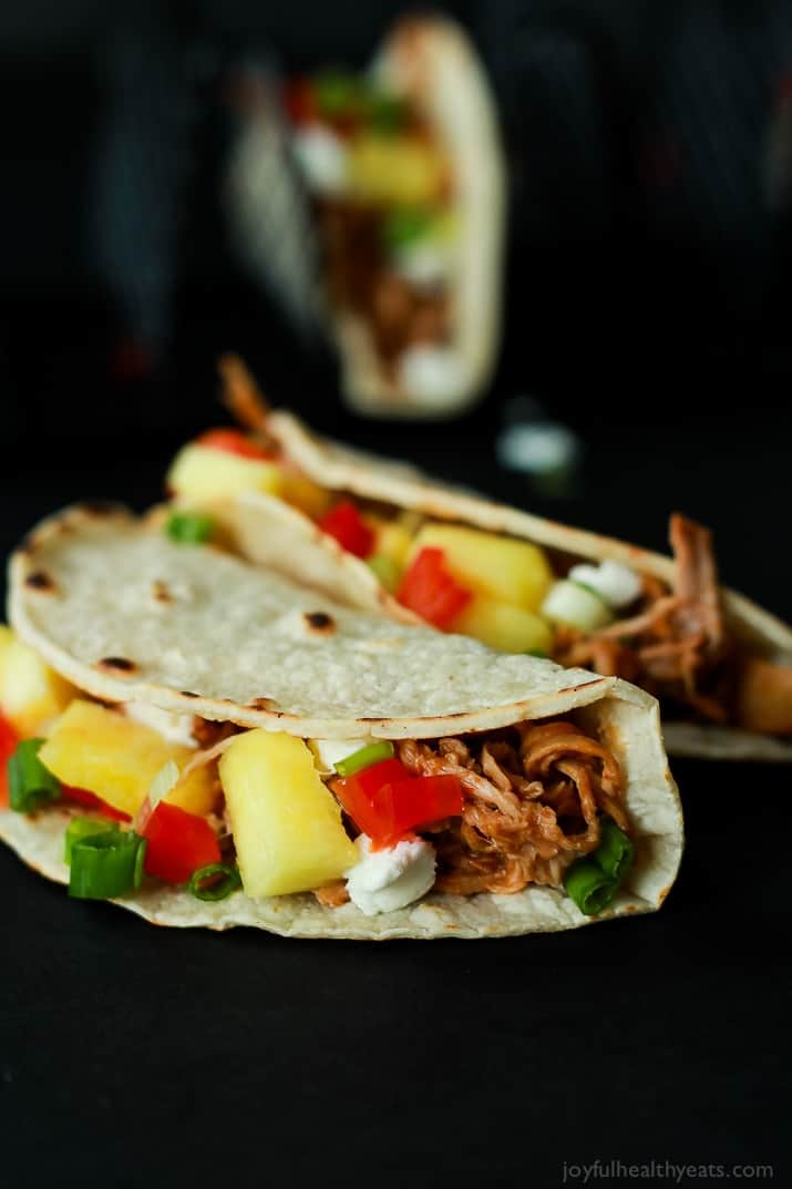 An easy Crock Pot Recipe your family will love! Hawaiian Pork Tacos filled with sweet pulled pork, fresh pineapple, red peppers, and goat cheese for a fun twist!! |joyfulhealthyeats.com #recipes Two Hawaiian Pork Tacos filled with sweet pulled pork, fresh pineapple, red peppers, and goat cheese