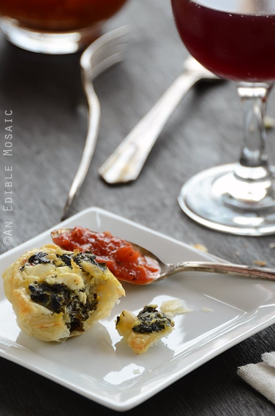32 Easy Party Appetizers 西班牙皮塔泡芙放在一个方形盘子上,旁边是一杯葡萄酒