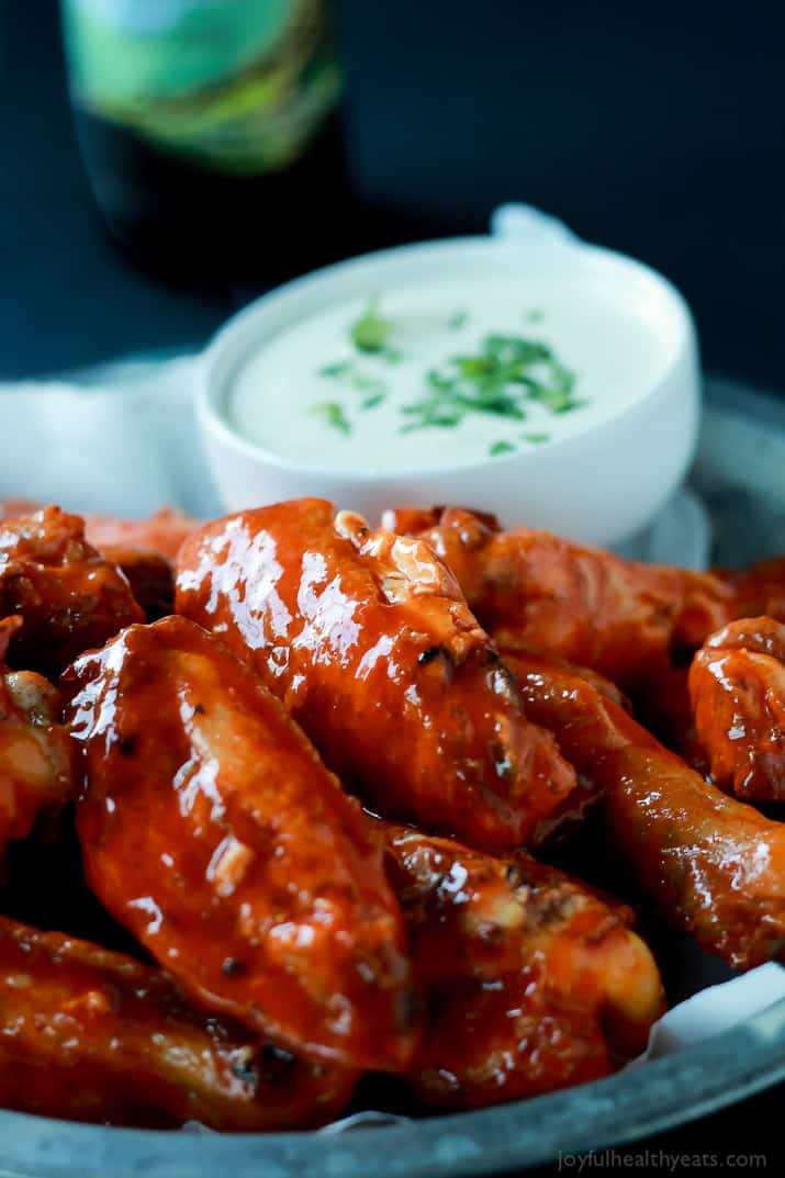 A healthier version of the Classic Buffalo Baked Chicken Wings, these are baked and still have the same crispy sauce taste! | m.albarakaa.com #recipes #appetizer 布法罗烤鸡翅放在盘子里,配上一杯奶油蘸酱