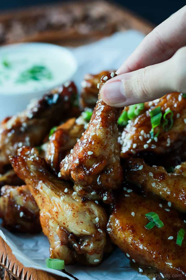 The BEST sauce ever and only for 4 ingredients, this is a must make! Tangy Honey Mustard Baked Chicken Wings | m.albarakaa.com #appetizer #recipes 手从一堆烤鸡翅中拿起一只鸡翅