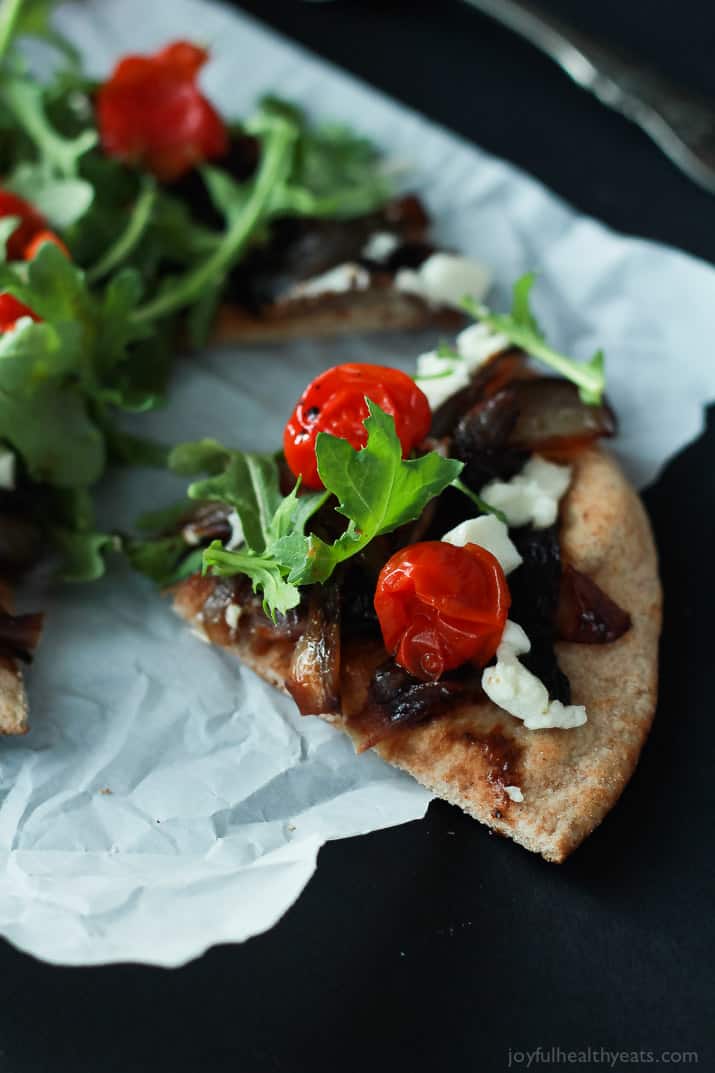 Add this low carb recipe to your collection of 30 minute meals; Pita Pizza that's not shy on flavor. | m.albarakaa.com #vegetarian #recipes 特写的一片皮塔披萨与香焦糖洋葱,番茄,羊乳酪和芝麻菜