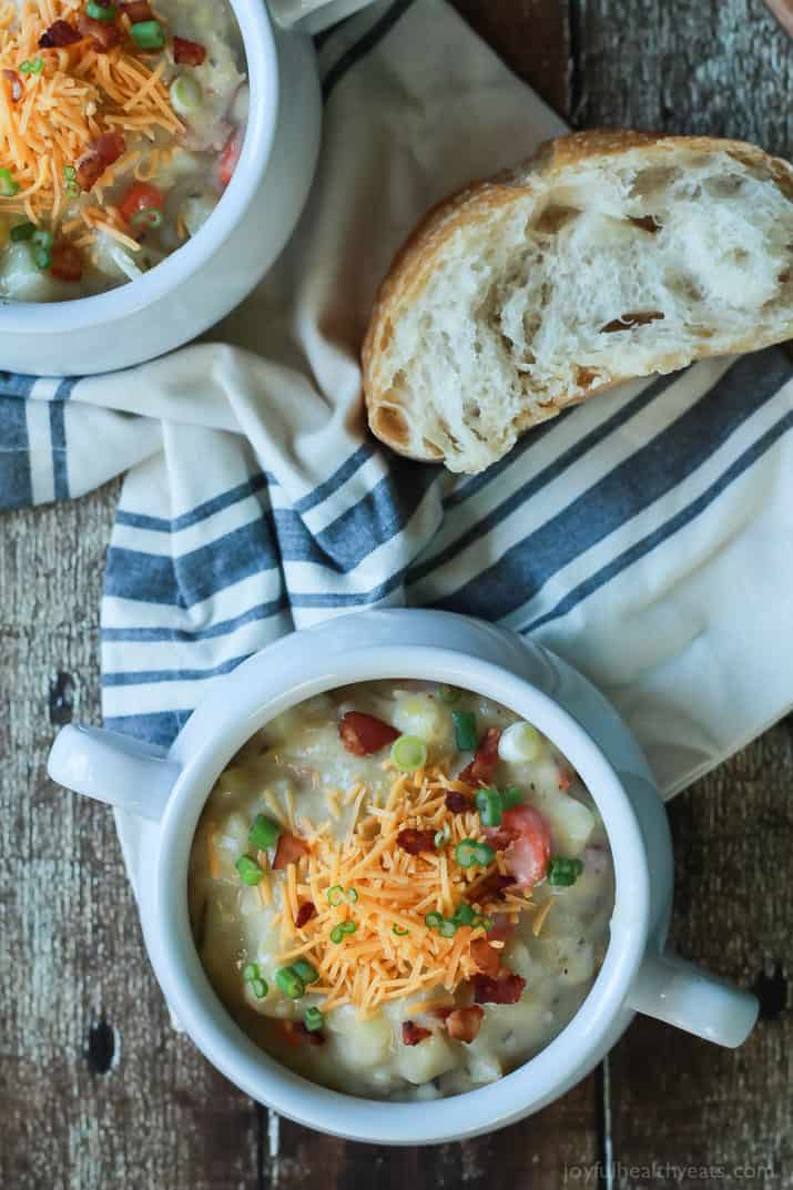 Creamy Potato Leek Soup, the ultimate comfort food soup made healthier with 2% milk, greek yogurt, and extra vegetables. De-lish! | joyfulhealthyeats.com #recipes #glutenfree 俯视图两罐奶油土豆韭菜汤旁边一块硬面包