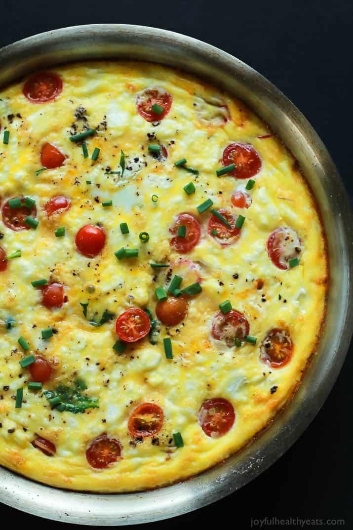 A Cheesy Bacon Spinach Frittata done in 30 minutes! This Spinach Frittata is packed with goat cheese, roasted red peppers, and bacon! Perfect for Brunch! | joyfulhealthyeats.com #easter #mothersday #recipes 平底锅里的芝士培根菠菜蛋饼俯视图