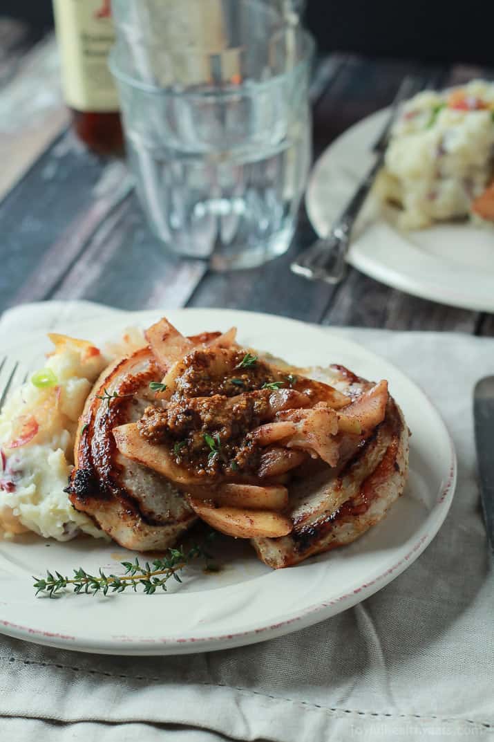 Mustard Crusted Pork Chops with Bourbon Glazed Apples 芥末猪排配波旁苹果,背景为两个玻璃杯