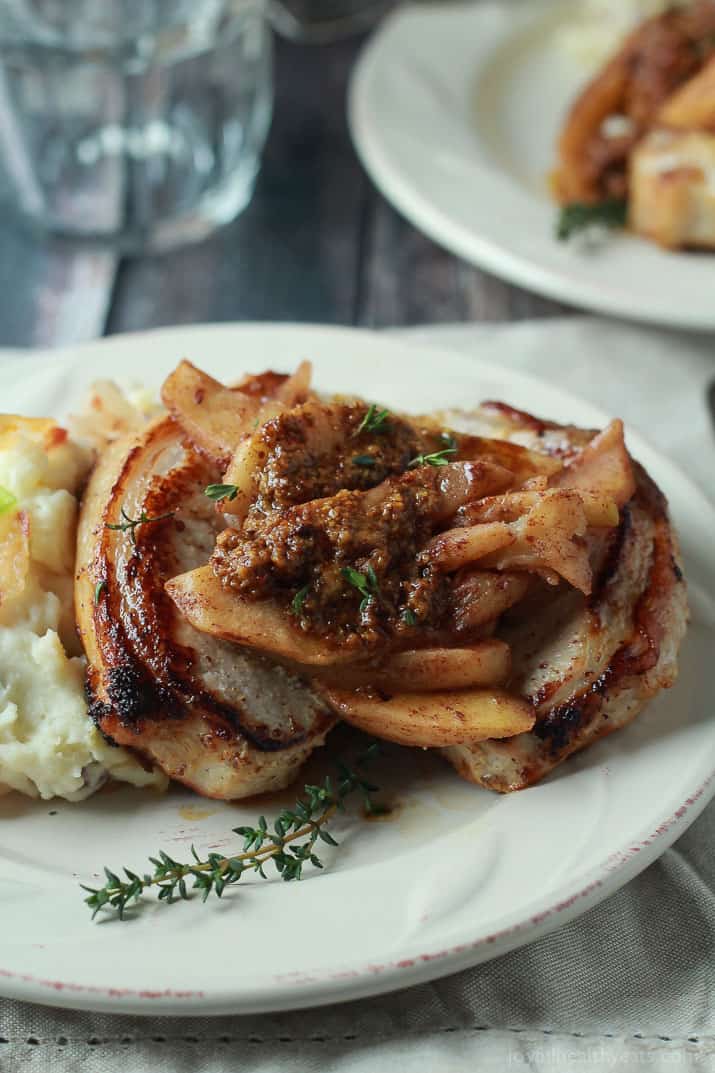 Mustard Crusted Pork Chops with Bourbon Glazed Apples 白盘子上的芥末猪排配波旁苹果
