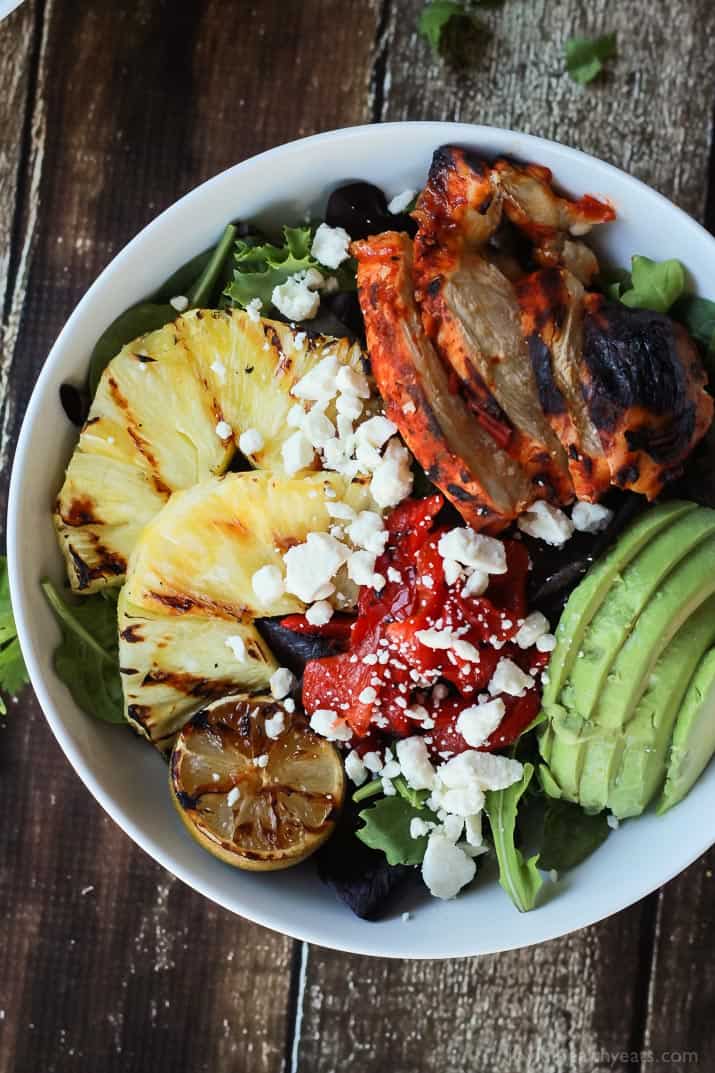 Harissa Lime Grilled Chicken Salad with a Creamy Cilantro Lime Vinaigrette, filled with grilled pineapple, limes, fresh avocado and an amazing dressing! Add to your list! | joyfulhealthyeats.com #glutenfree #recipes Top view of a bowl of Harissa Lime Grilled Chicken Salad with grilled pineapple, limes, and fresh avocado