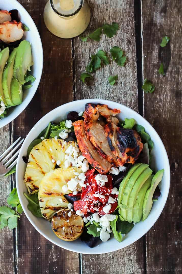 Harissa Lime Grilled Chicken Salad with a Creamy Cilantro Lime Vinaigrette, filled with grilled pineapple, limes, fresh avocado and an amazing dressing! Add to your list! | joyfulhealthyeats.com #glutenfree #recipes Top view of Harissa Lime Grilled Chicken Salad in a bowl with grilled pineapple, sliced avocado, roasted red pepper and crumbled feta