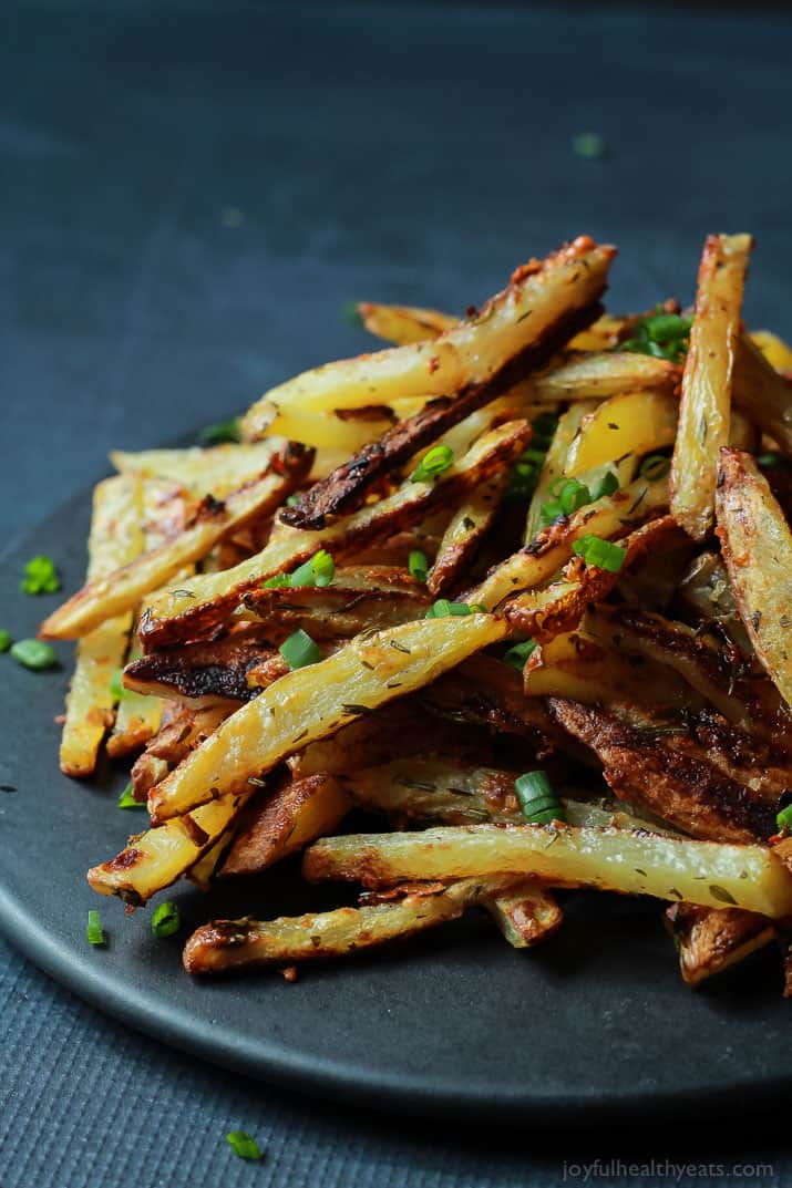 Crispy Baked Garlic Parmesan Fries are crispy on the outside and soft on the inside, the easiest skinny Baked Fries you will ever make! Only 6 ingredients but pack a phenomenal fresh herb taste! | joyfulhealthyeats.com #recipes #glutenfree 香脆蒜味帕尔玛干酪薯条和大葱堆在盘子里