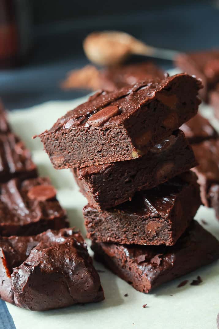 The Best Fudgy Avocado Brownies you will ever taste, packed with coconut sugar, chocolate chips, and coffee! The perfect guilt free dessert recipe for the summer! | joyfulhealthyeats.com #recipes Close-up of a stack of Fudgy Avocado Brownies on parchment paper