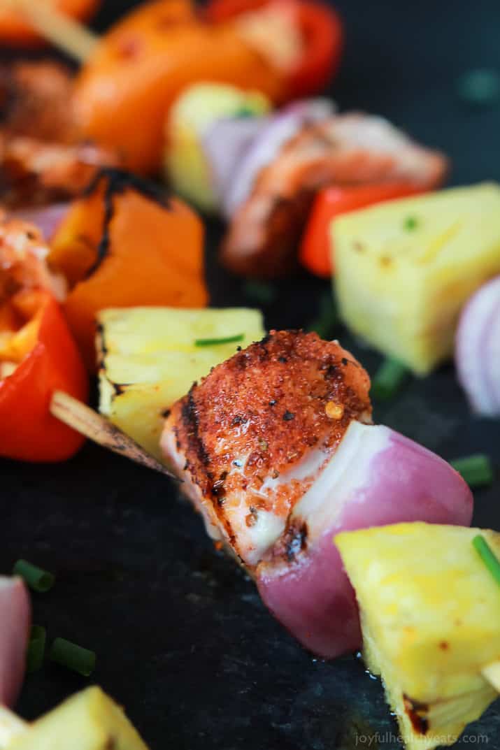 Caribbean Grilled Salmon Kabobs will take you straight to the islands with the cajun spices, fresh pineapple, bell peppers, and fresh seafood! Perfect healthy grilling recipe for the summer done in 20 minutes! | joyfulhealthyeats.com #recipes 特写镜头视图的加勒比烤三文鱼kabobs与cajun香料,新鲜的菠萝,甜椒和新鲜的海鲜