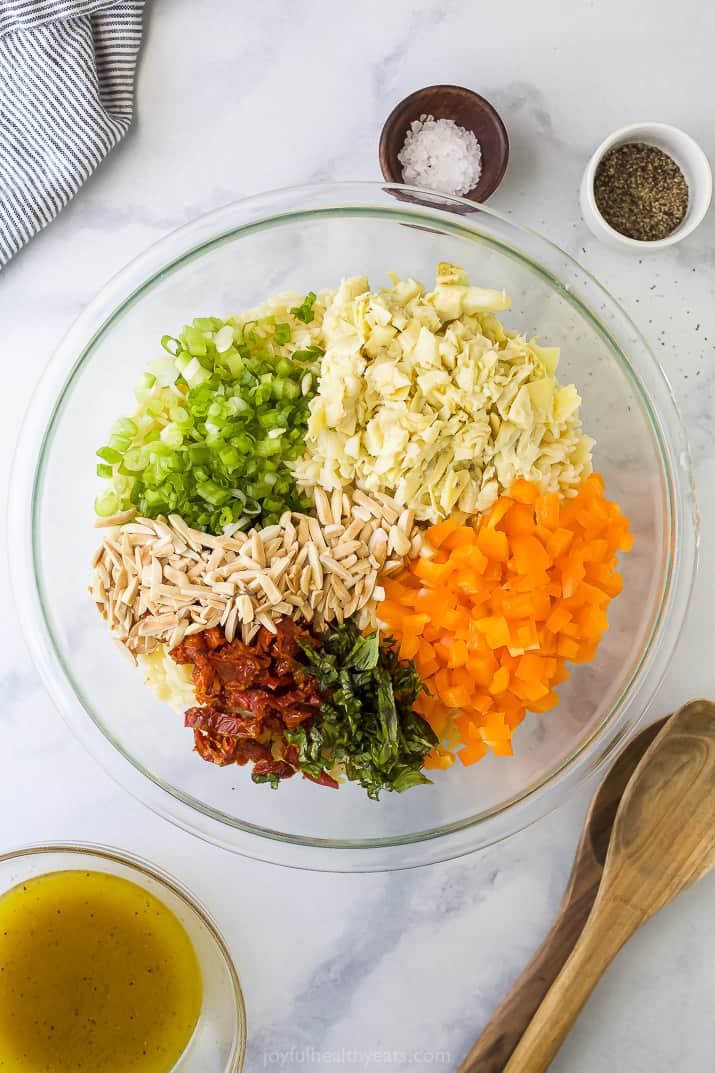 Mediterranean Orzo Pasta Salad 一个碗里装满了碎片的杏仁,为奥罗沙拉制作的蔬菜
