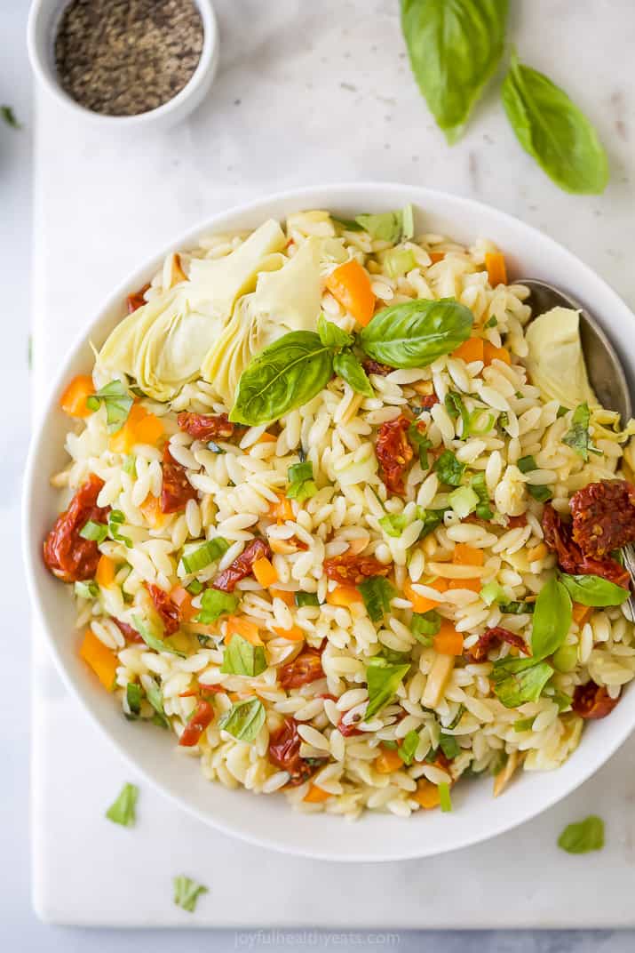 Mediterranean Orzo Pasta Salad 一个白色的碗装满了地中海意大利面沙拉在placemat