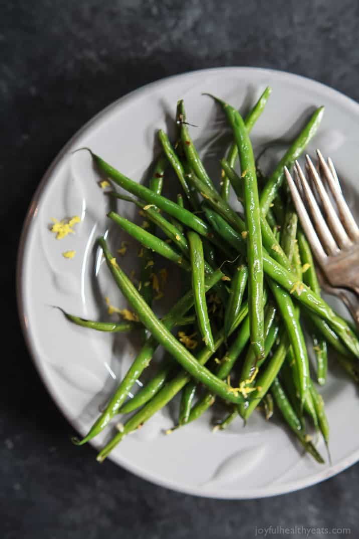 Easy Skillet Green Beans 白盘上有一堆青豆、柠檬和大蒜