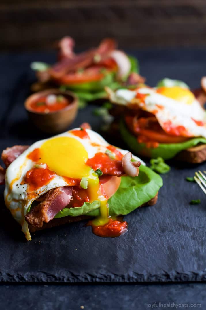 Open Faced BLT Sandwich with Harissa 特写镜头射击了在黑服务盛肉盘的一个开放的面孔的blt三明治