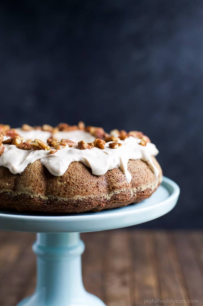 Pumpkin Bundt Cake with Cream Cheese Frosting 一个南瓜束蛋糕在一个灰色的蛋糕架与海军蓝背景