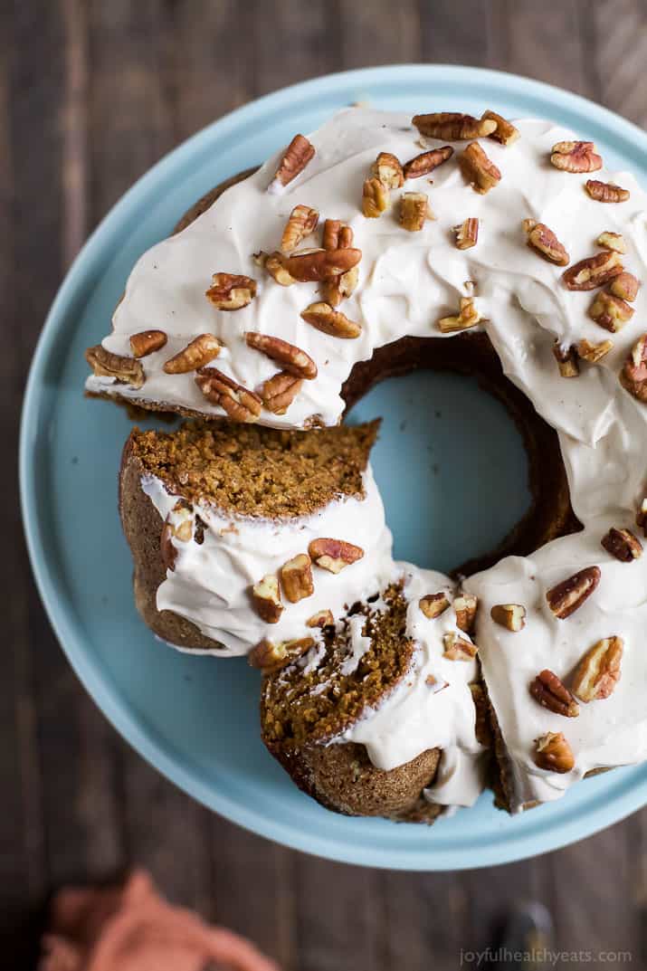 Pumpkin Bundt Cake with Cream Cheese Frosting 从架子上的蛋糕上切下两片南瓜饼
