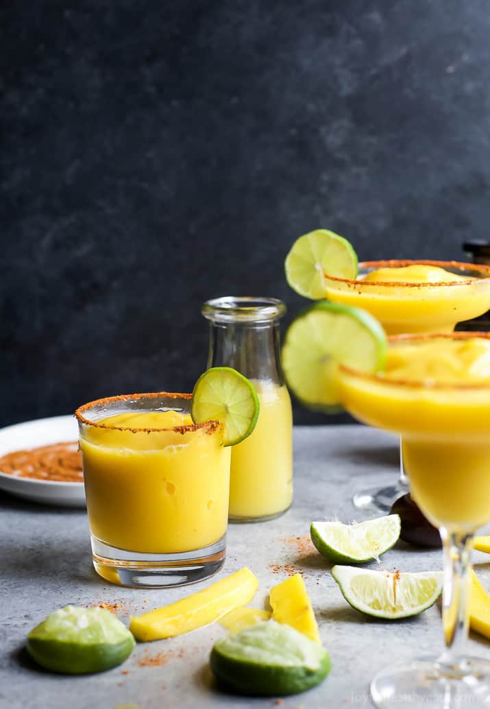 一杯冰冻芒果玛格丽塔酒,边缘有红辣椒、酸橙和盐