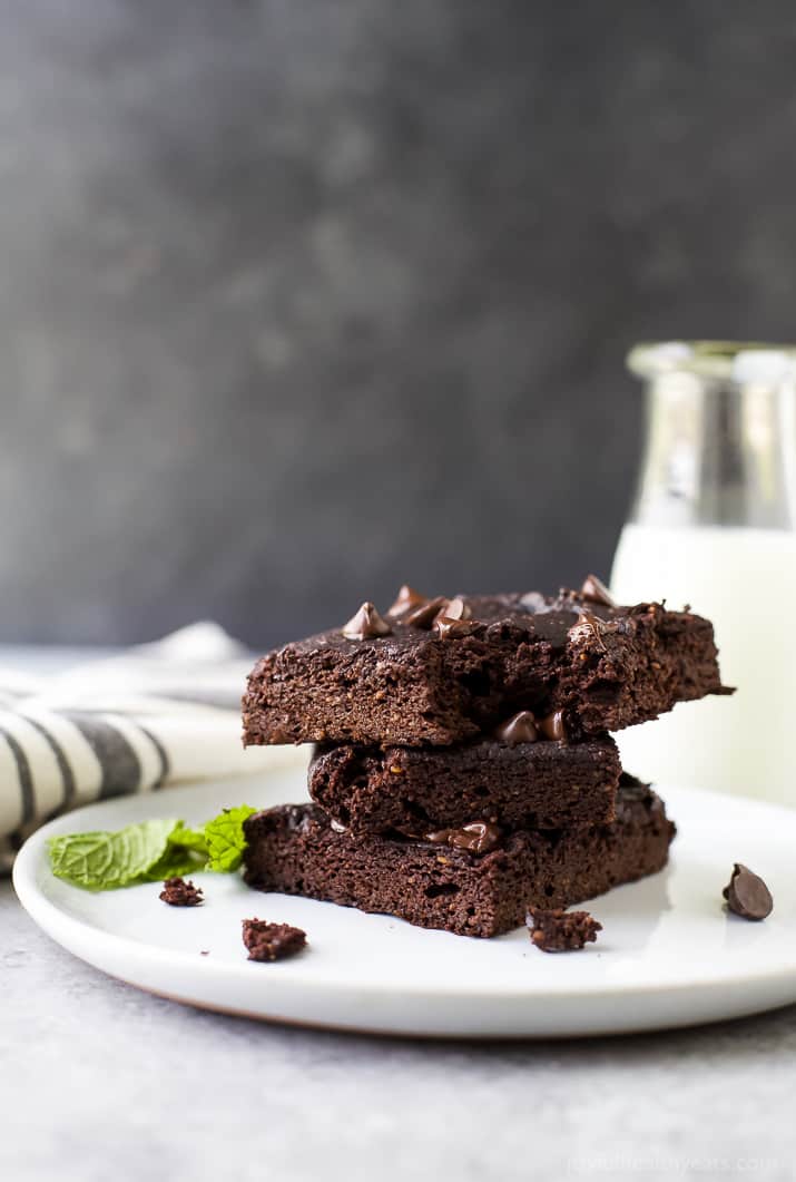Fudgy Flourless Pumpkin Brownies 盘子里有三块南瓜布朗尼蛋糕和两片薄荷叶