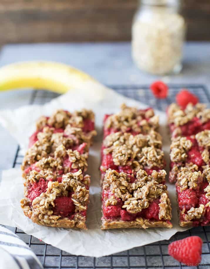 Almond Oat Raspberry Bar Recipe 冷架上的树莓棒,背景是香蕉和一罐燕麦