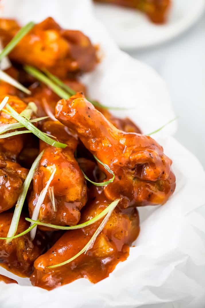关闭被烘烤的甜和辣bbq鸡翼的旁边照片在篮子