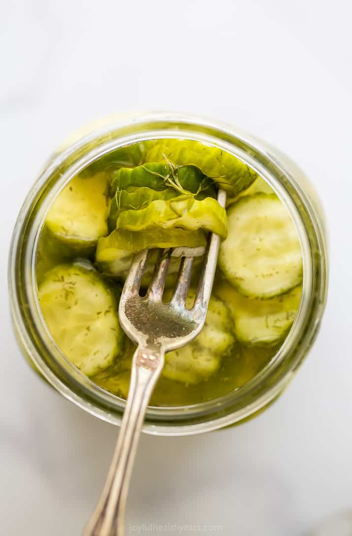 叉子和泡菜放在一个装满莳萝泡菜的罐子里