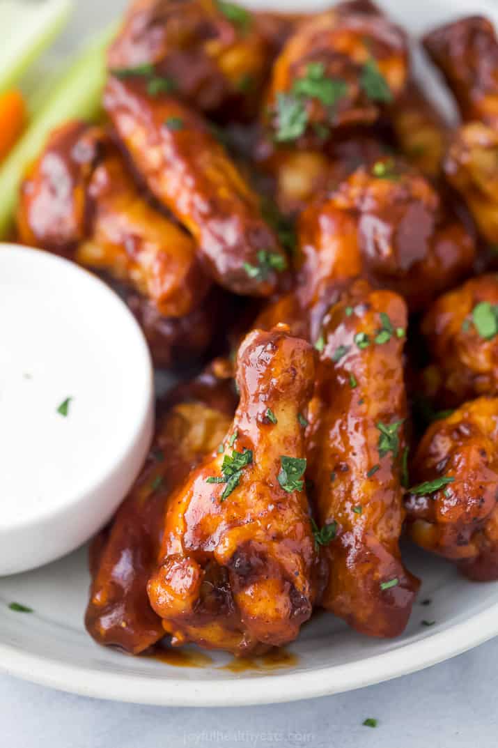 The Crispiest Honey BBQ Air Fryer Chicken Wings 空气炸鸡翅在一个白色的盘子和一边的牧场