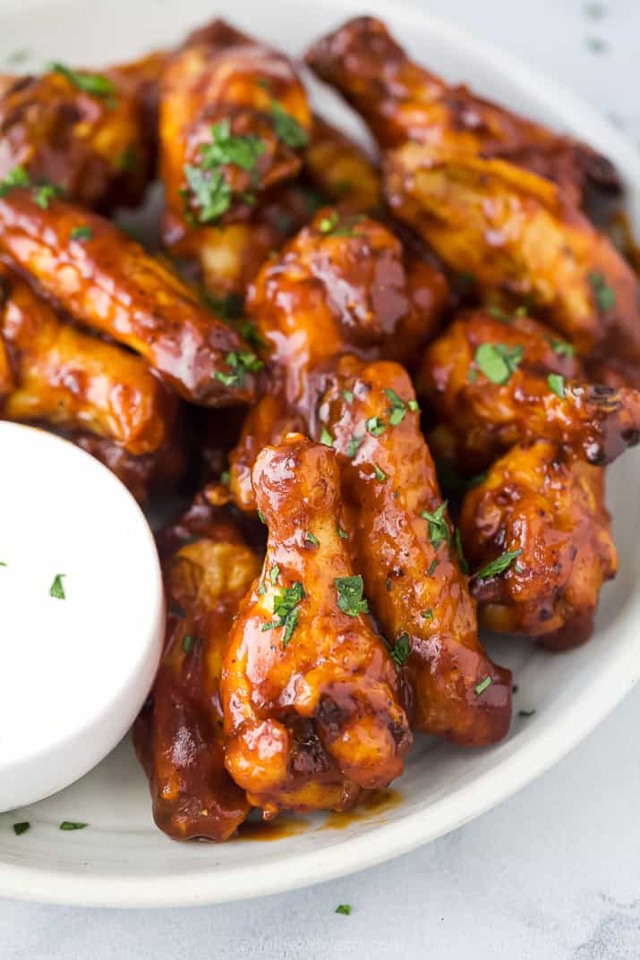 The Crispiest Honey BBQ Air Fryer Chicken Wings 一个近距离拍摄的一堆翅膀覆盖在蜂蜜烧烤酱