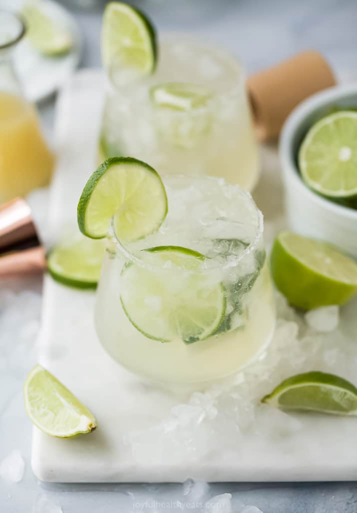 The Ultimate Skinny Margarita Recipe 在一个切板的两个玛格丽塔酒与石灰楔子和被击碎的冰