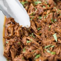 用钳子夹起慢炖的烤肉卷