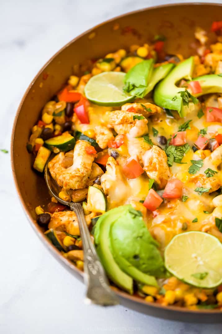 closeup side photo of 30 minute zucchini chicken enchilada skillet in a pan topped with avocado