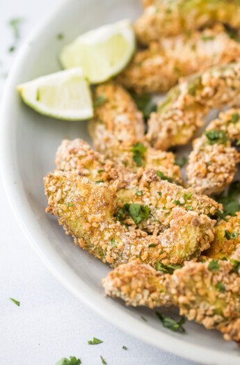 crispy avocado fries on a plate with lime wedges
