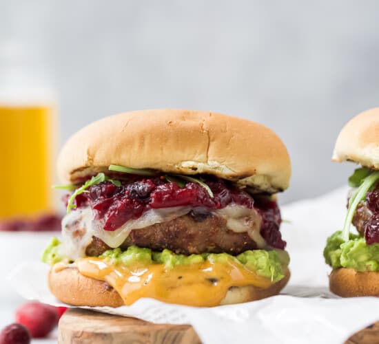 菜板上放着牛油果火鸡汉堡，上面抹着红莓酸辣酱