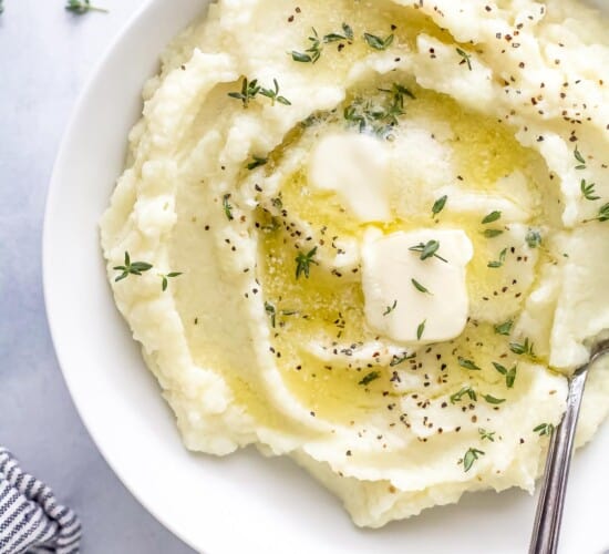 A bowl of mashed cauliflower beside a striped kitchen towel on a countertop
