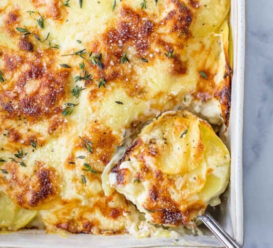 spoon scooping cheesy scalloped potatoes